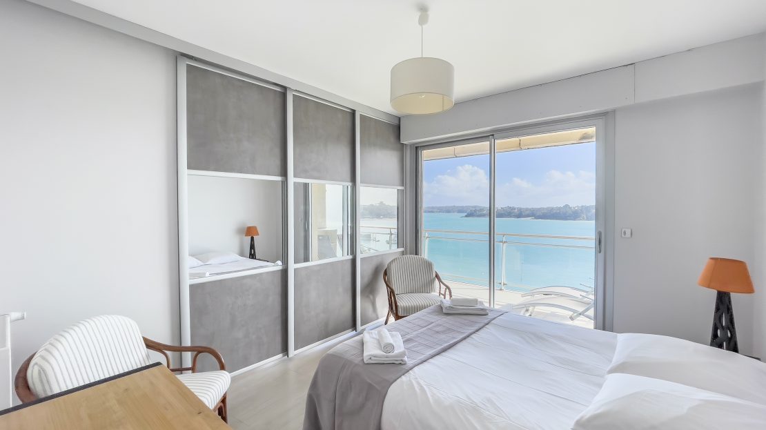 Chambre moderne avec lit, bureau et vue sur la mer à travers une grande baie vitrée