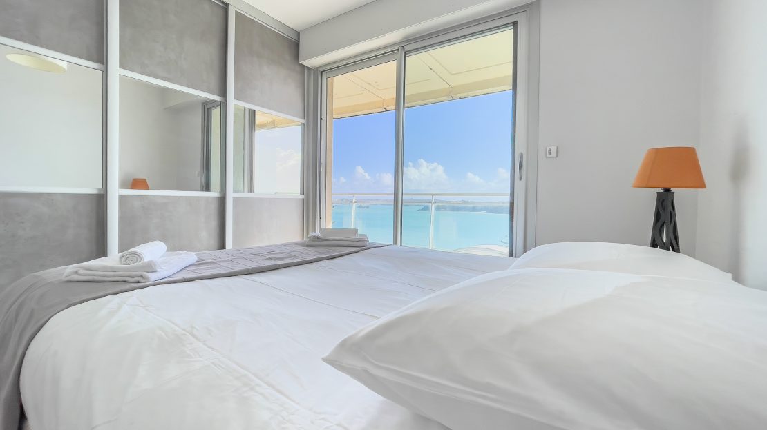 Chambre moderne avec lit confortable et vue sur la mer à travers une grande baie vitrée