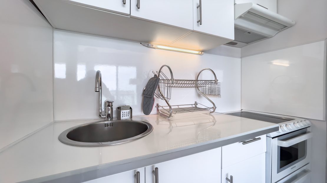 Cuisine moderne blanche avec évier, four et hotte de cuisine