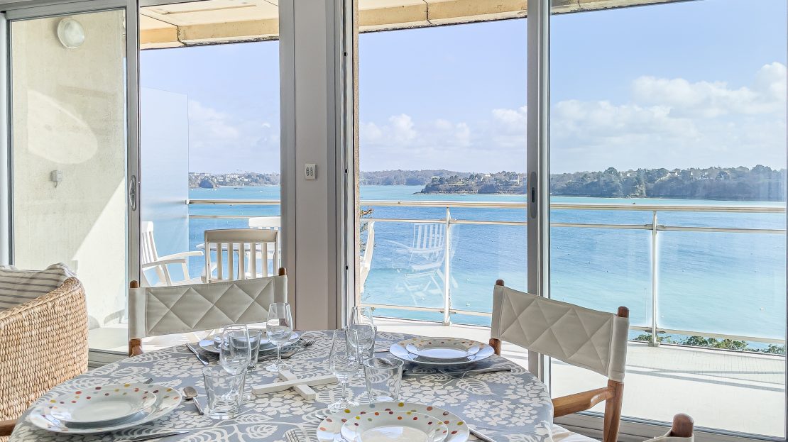 Voici les informations que je propose pour améliorer le référencement de l'image : Nom de fichier : "salle-a-manger-avec-vue-sur-la-mer-et-terrasse.jpg" Texte alternatif (alt) : "Salle à manger avec table dressée et vue sur la mer à travers des baies vitrées