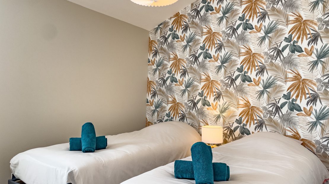 Chambre d'hôtel avec deux lits et papier peint tropical