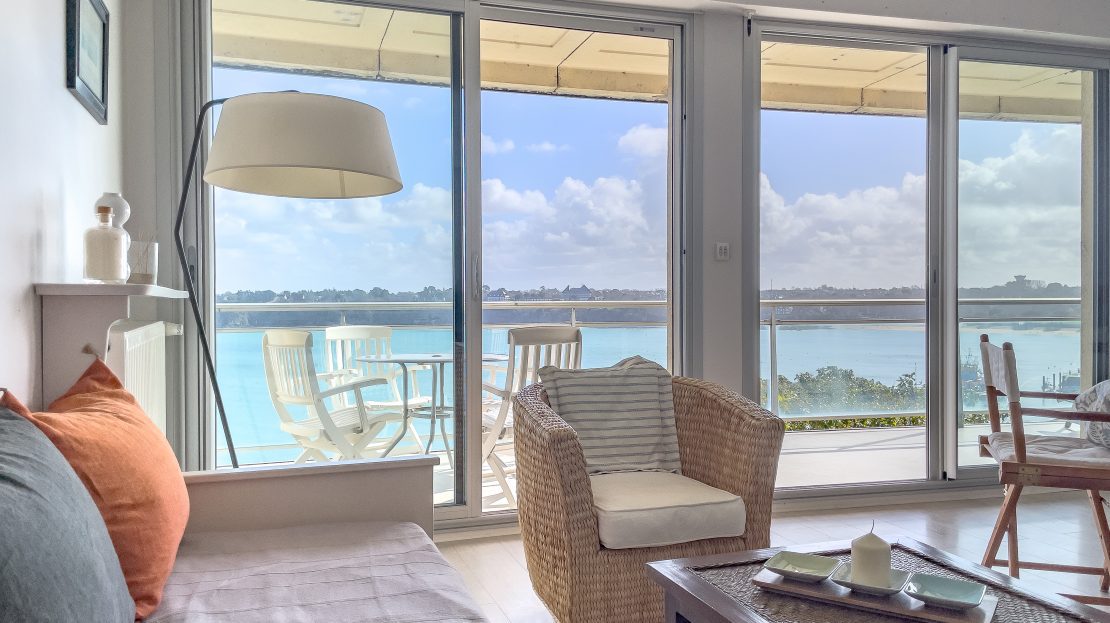 Salon moderne avec vue sur la mer et terrasse à travers des baies vitrées
